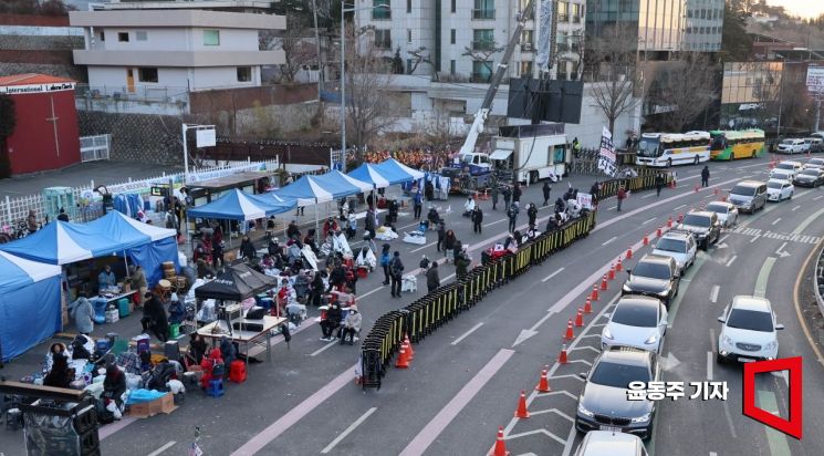 10일 서울 용산구 한남동 대통령 관저 부근에서 윤석열 대통령 지지자들이 지나가는 차량들을 향해 태극기와 성조기를 흔들고 있다. 윤동주 기자