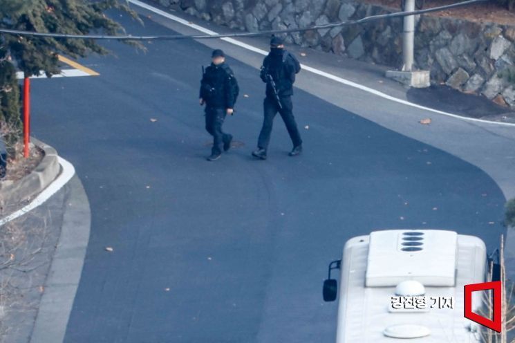 7일 서울 용산구 대통령 관저에서 검정옷을 착용하고 총기를 착용한 관저 근무자가 이동하고 있다.