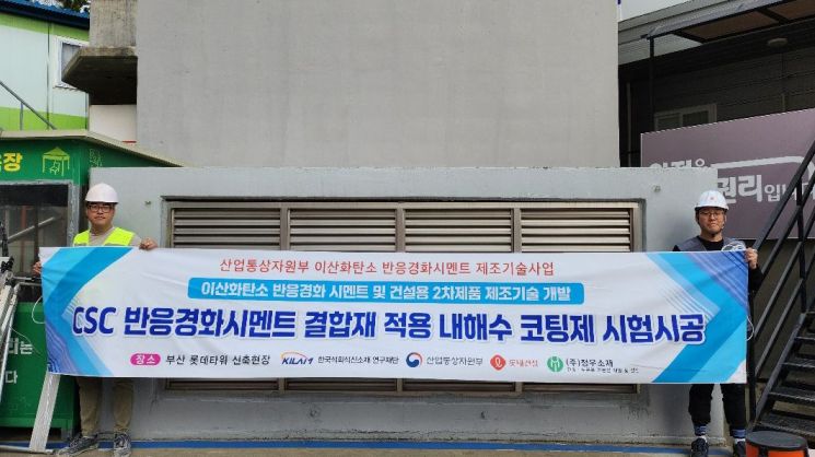 롯데건설 직원들이 부산 롯데타워 현장에서 이산화탄소 반응경화 시멘트를 활용한 코팅제를 시공하고 기념촬영을 하고 있다. 롯데건설 제공