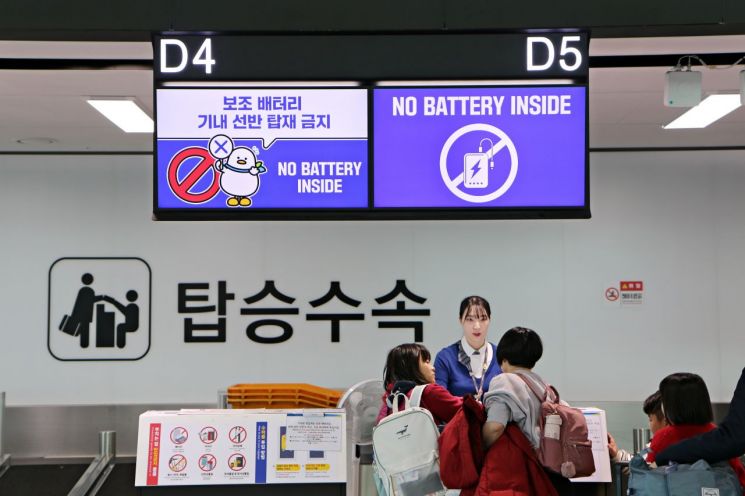 에어부산 탑승수속 카운터에서 직원이 탑승객들에게 기내 배터리 직접 소지에 대해 안내하고 있다.