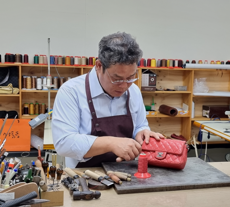 Specialist restoring designer handbags inside a professional workshop.