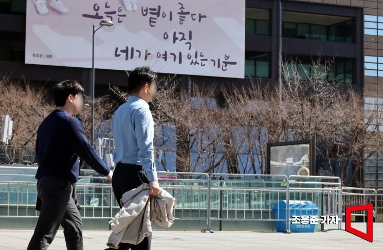 지난달 26일 종로구 광화문광장을 찾은 시민들이 겉옷을 벗어 손에 들고 이동하고 있다.