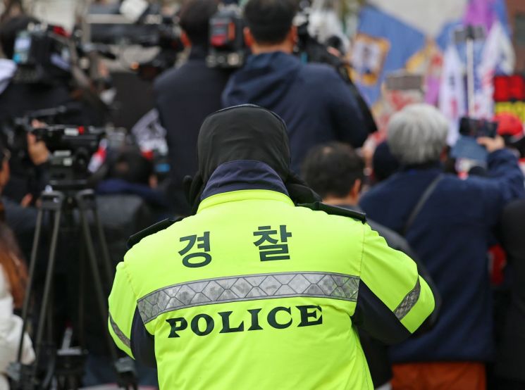 지난달 28일 서울 종로구 성균관대학교 앞에서 열린 윤석열 대통령 탄핵 반대 집회 측 스피커 앞에 선 경찰들이 귀를 막고 있다. 연합뉴스