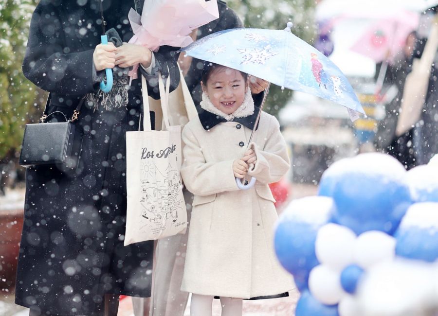 4일 서울 마포구 아현초등학교에서 열린 입학식에서 신입생 가족이 눈을 맞으며 강당으로 향하고 있다. 연합뉴스