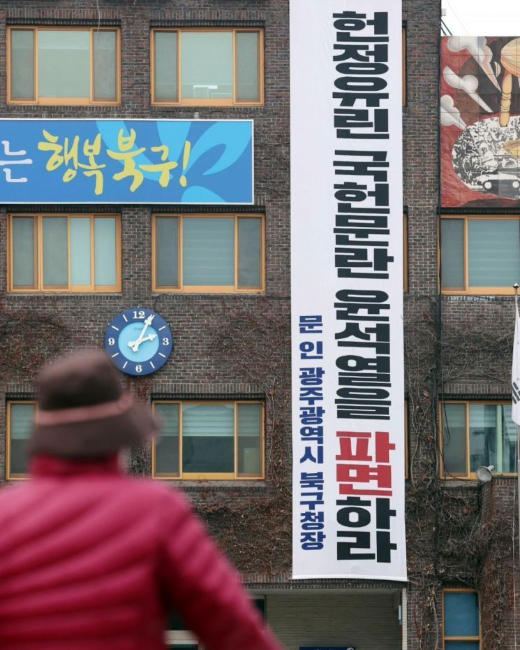 지난 10일 문인 광주 북구청장이 청사 외벽에 건 "헌정유린 국헌문란 윤석열을 파면하라" 현수막 앞을 한 시민이 지나고 있다. 문인 북구청장 페이스북 갈무리