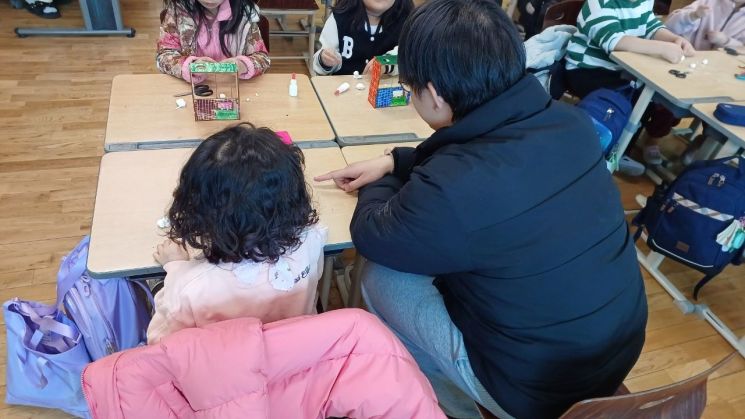 19일 오정초에서 한 대학생 보조강사가 한 학생을 지도하고 있다.