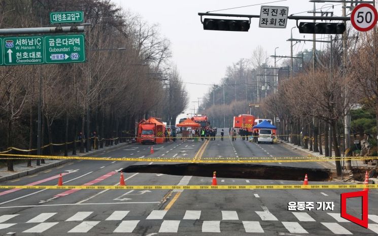지난 3월 24일 서울 강동구 대명초등학교 인근 사거리에서 4개차로에 걸친 '대형 싱크홀(땅꺼짐)' 이 발생했다. 25일 사고 현장 주변이 통제되고 있다. 싱크홀에는 승용차 1대와 오토바이 1대가 빠졌으며, 승용차 탑승자 1명은 인근 병원으로 이송됐다. 현재 싱크홀 아래에는 오토바이 운전자 1명이 매몰돼 있다. 깊이는 30m로 추정된다. 2025. 03. 25 윤동주 기자