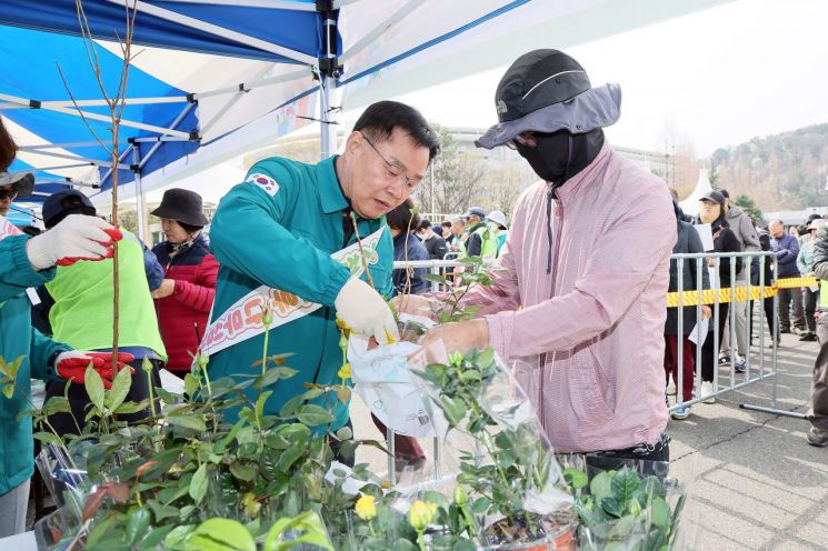 홍남표 창원특례시장이 시민에게 나무를 나눠주고 있다.