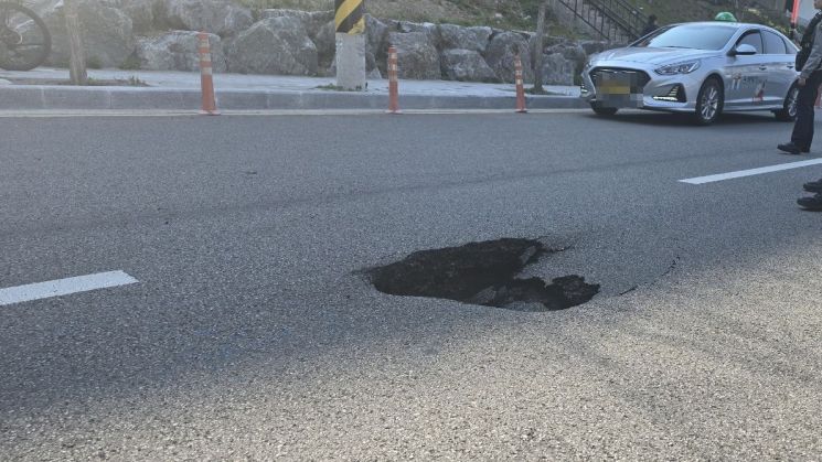 부산 사하구의 한 도로에서 약 70cm 지름의 땅 꺼짐이 발생했다. 사하구는 도로를 통제하고 복구 작업을 벌이고 있다. 부산경찰청 연합뉴스