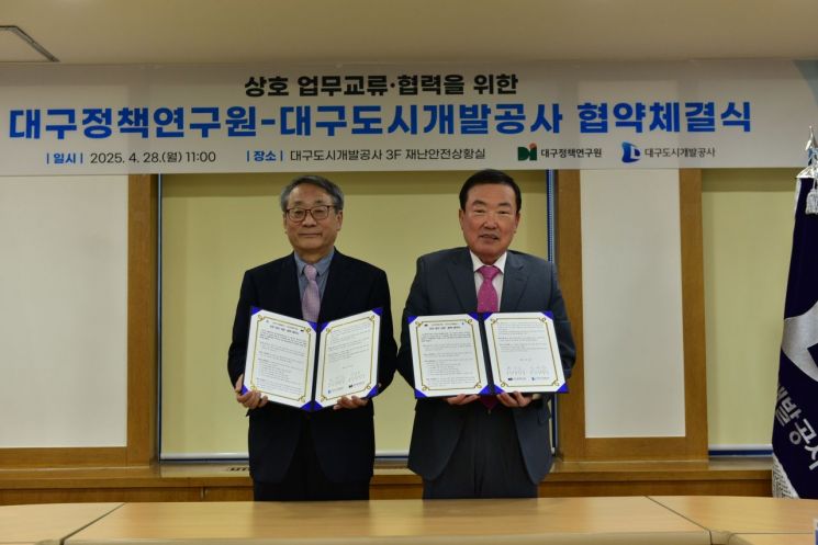 정명섭 대구도시개발공사 사장(오른쪽)과 박영호 대구정책연구원장이 지역개발 공동연구를 위해 업무협약을 체결한 뒤 협약서를 들어보이고 있다.