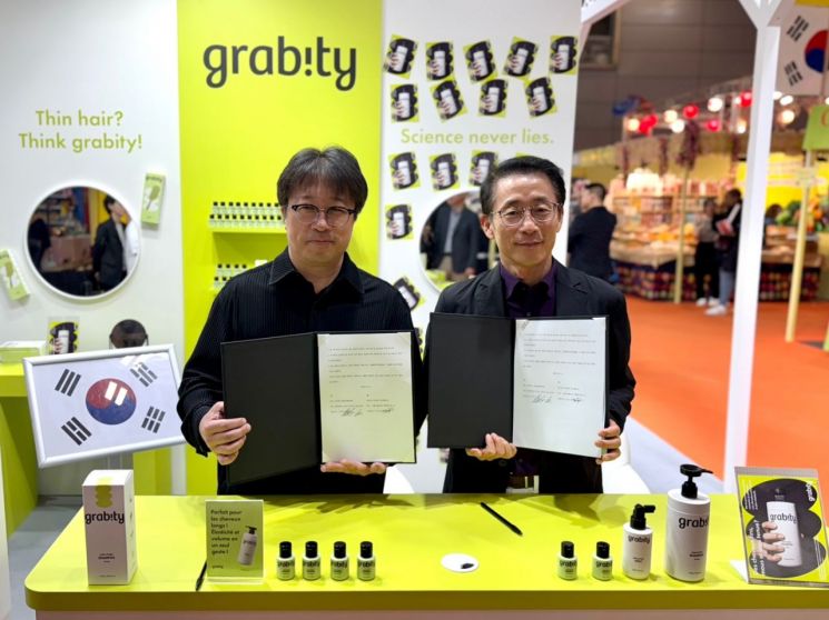 이해신 폴리페놀팩토리 대표(왼쪽)와 김재겸 롯데홈쇼핑 대표가 11일 프랑스 파리 포르트 드 베르사유 전시장에서 기능성 탈모샴푸 '그래비티'의 해외수출을 위한 독점 계약을 체결한 뒤 기념촬영하고 있다. 롯데홈쇼핑 제공