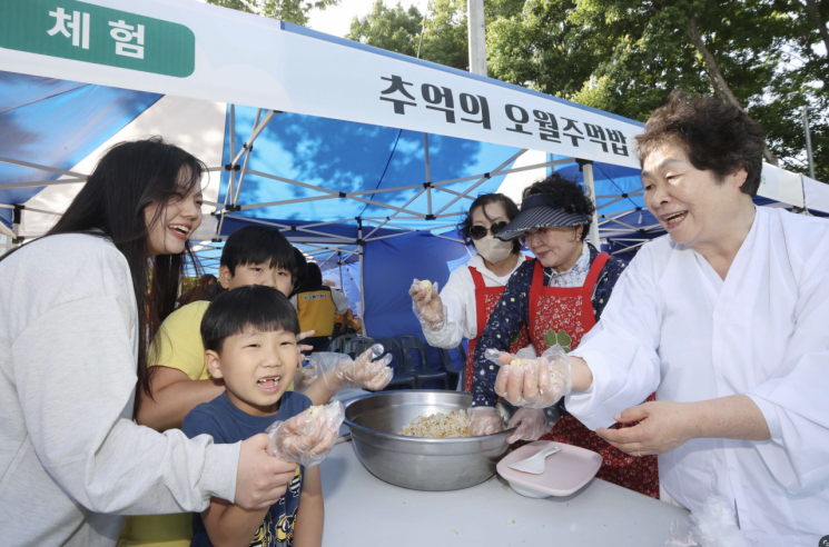 5·18 관련 체험 부스에서 ‘오월 주먹밥 만들기’에 참여한 아이들과 주민들이 웃으며 주먹밥을 빚고 있다. 광주북구마을자치도시재생센터 제공