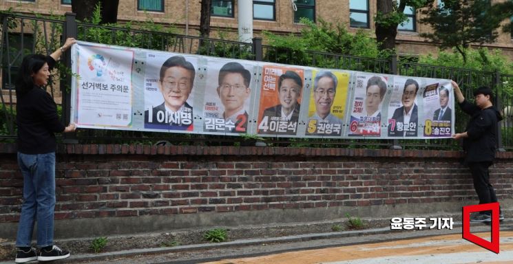 15일 서울 종로구 예술가의집 인근 담에 서울시 선관위 관계자들이 제21대 대통령선거 후보자 선거벽부를 붙이고 있다. 윤동주 기자