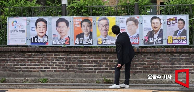15일 서울 종로구 예술가의집 인근 담에 서울시 선관위 관계자들이 제21대 대통령선거 후보자 선거벽부를 붙이고 있다. 2025.05.15 윤동주 기자