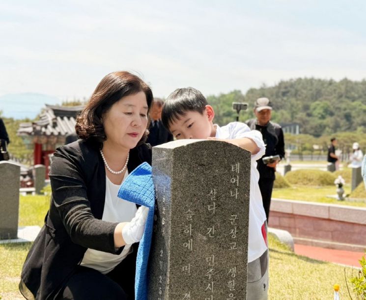 정경남 효령타운 본부장이 5.18 기념행사에 참여한 어린이집 원생과 함께 묘비를 닦으면서 오월정신을 기리고 있다. 광주 효령타운 제공