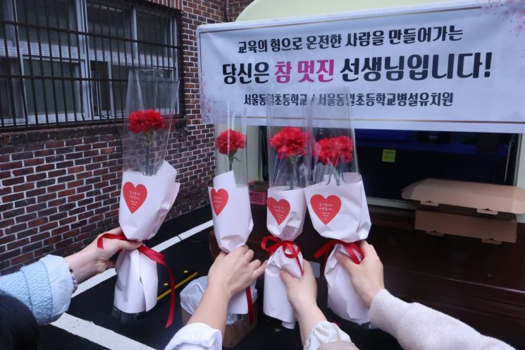 스승의날인 15일 서울 노원구 동일초등학교에서 선생님들이 학생들에게 받은 카네이션을 들고 기념촬영을 하고 있다. 연합뉴스