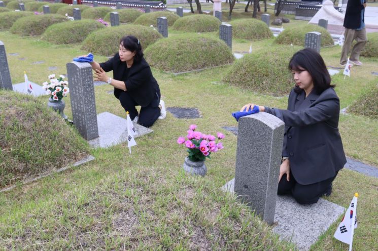 광주사회서비스원 임직원들이 15일 국립5·18민주묘지에서 오월 영령들의 묘비를 닦고 있다. 광주사회서비스원 제공