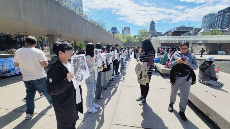 광주 학생들이 지난 18일 캐나다 토론토 네이슨 필립스 스퀘어에서 ‘광주정신, 위대한 유산’ 5·18 기록과 진실을 담은 사진전을 개최했다. 광주 학생들이 든 40여점의 사진을 캐나다 시민들이 지켜보고 있다. 광주교육청 제공