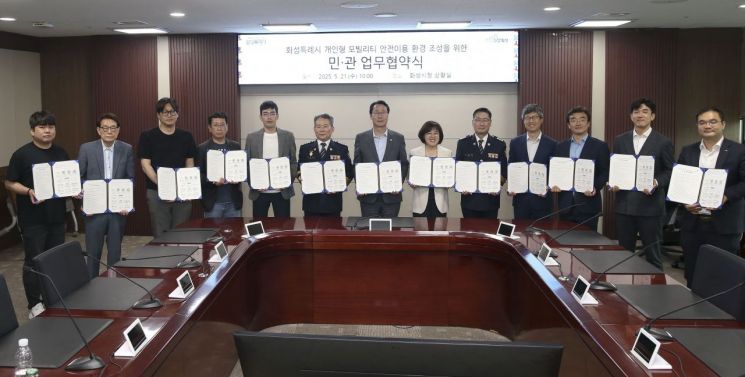 21일 화성시청 상황실에서 열린 개인형이동장치(PM) 안전이용 문화 조성을 위한 업무협약식에서 정명근 화성시장(왼쪽 7번째) 등 참석자들이 협약서를 들어보이고 있다. 화성시 제공