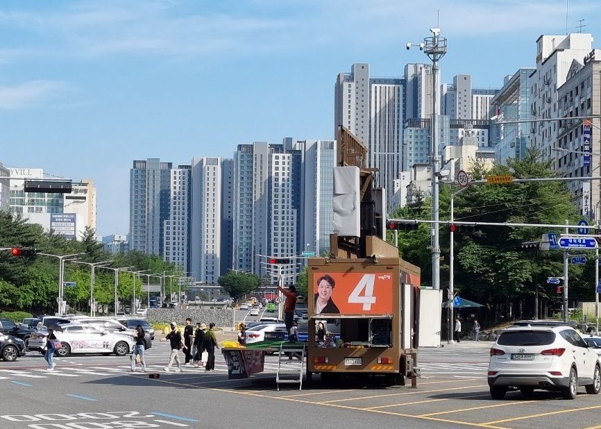 이준석 개혁신당 대선 후보의 유세차량이 26일 대전 서구 둔산동 번화가 사거리 한복판에서 음악을 크게 틀고 선거 유세를 하고 있는 가운데, 그 앞을 행인들이 지나가고 있다. 대전=문혜원 기자