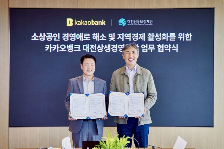▲김석 카카오뱅크 뱅킹그룹장(오른쪽)과 양필환 대전신용보증재단 이사장(왼쪽)이 28일 카카오뱅크 판교오피스에서 진행된 '카카오뱅크 대전상생경영통장 업무 협약식'에서 기념 촬영을 하고 있다. 카카오뱅크 제공