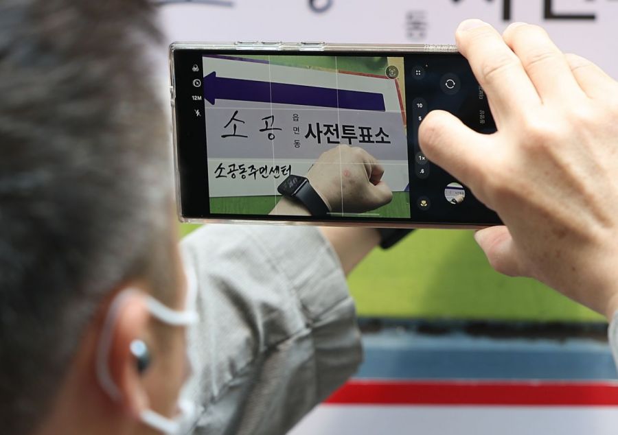 서울 시내 한 사무실에서 사전투표를 마친 유권자들이 투표에 참여하며 기표 도장을 찍은 다양한 '투표 인증 용지'들을 보여주고 있다. 오른쪽 사진은 서울 중구 소공동주민센터에서 투표를 마친 유권자가 인증샷을 찍고 있는 모습. 연합뉴스