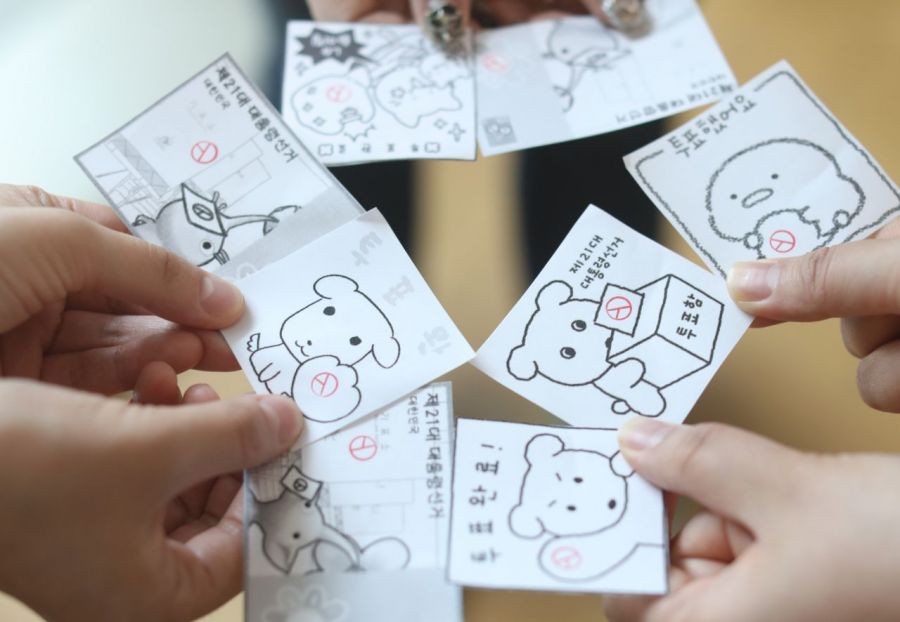 서울 시내 한 사무실에서 사전투표를 마친 유권자들이 투표에 참여하며 기표 도장을 찍은 다양한 '투표 인증 용지'들을 보여주고 있다. 오른쪽 사진은 서울 중구 소공동주민센터에서 투표를 마친 유권자가 인증샷을 찍고 있는 모습. 연합뉴스