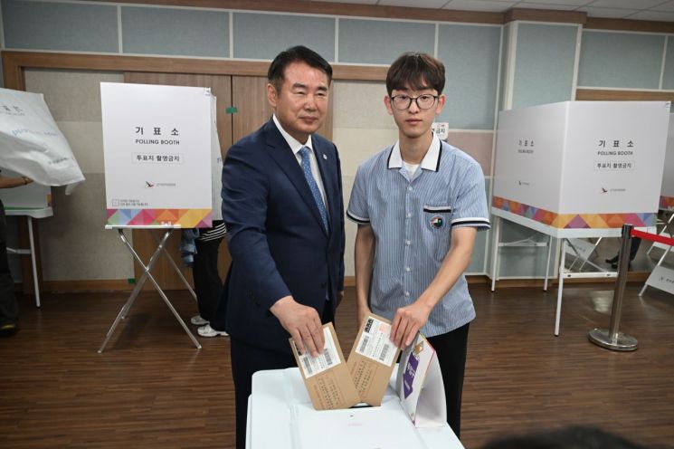 이정선 광주광역시교육감이 29일 화정2동 행정복지센터에 마련된 투표소에서 생애 첫 투표자가 된 광덕고 하유성 학생회 부회장과 투표함에 투표용지를 넣고 있다. 광주교육청 제공