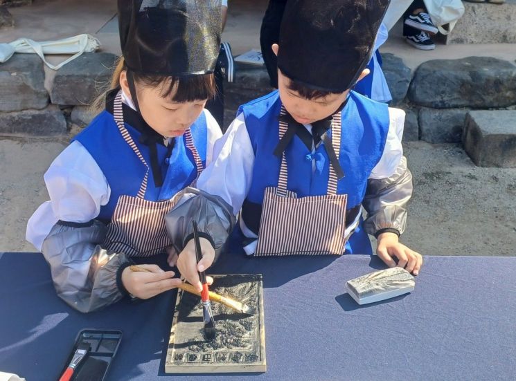 유생복을 입은 어린이들이 목판에 먹을 바르며 전통 인쇄 체험을 하고 있다. 장성군 제공