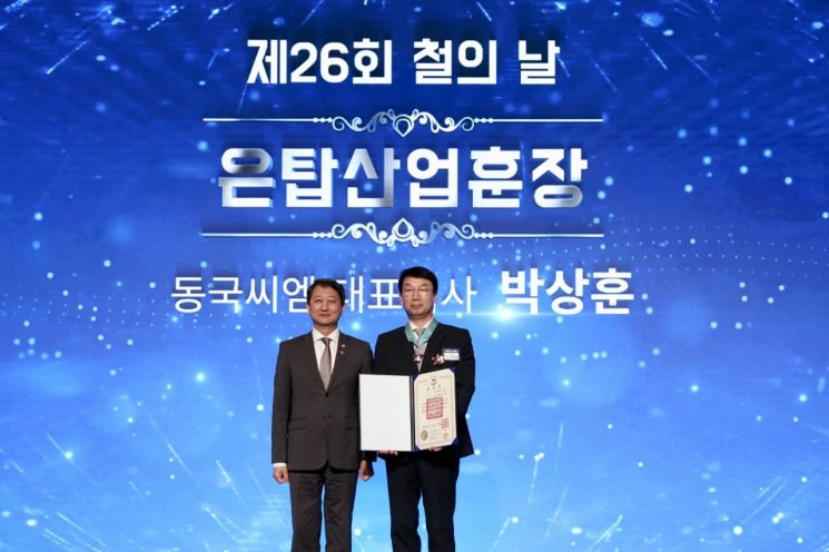 제26회 철의 날 은탑산업훈장을 수훈한 박상훈 동국씨엠 대표이사 사장(오른쪽)이 안덕근 산업부장관(왼쪽)과 기념사진을 찍는 모습. 동국제강 제공