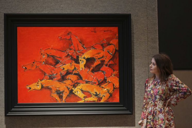 지난 2일 영국의 한 경매장에서 직원이 후세인의 작품 무제(Seven Horses of the Sun)를 보고 있다. AP연합뉴스