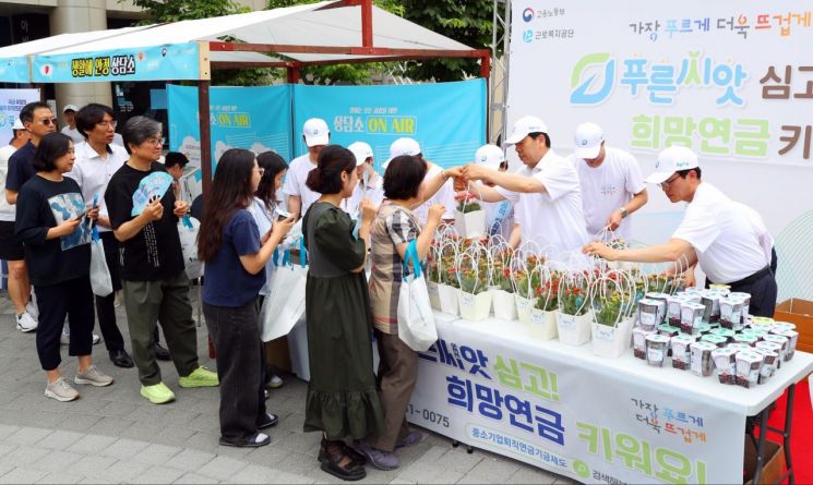 근로복지공단이  13일 서울 구로디지털단지역 인근에서 꽃 화분과 씨앗 키트 나눔 행사를 갖고 '푸른씨앗' 홍보를 하고 있다. 근로복지공단 제공