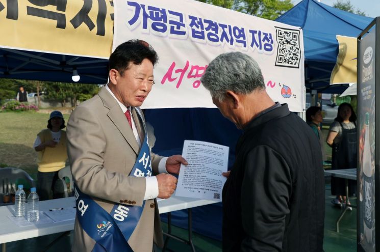서태원 군수(왼쪽)가 2024년 실시한 '범군민 서명운동'에서 주민으로부터 접경지역 서명을 받고 있다. 가평군 제공