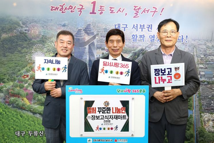 12년동안 매월 20만원씩을 기부해온 장보고식자재마트 진천점 김영진 점장(왼쪽)이 이태훈 대구 달서구청장(중앙)과 기념촬영을 하고 있다.