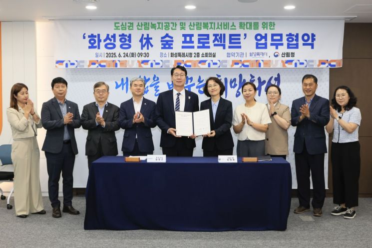 정명근 화성시장(앞줄 왼쪽)과 이미라 산림청 차장이 24일 화성시청 소회의실에서 개최된 '화성형 休 숲 프로젝트' 업무협약식에서 협약서를 들어보이고 있다. 화성시 제공