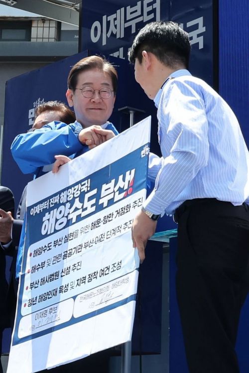 이재명 대통령이 이번 대선 당시인 지난달 14일 부산 부산진구 서면에서 권기흥 에이치라인해운해상직원노조 위원장과 해양수도 부산 협약서에 서명한 뒤 악수하고 있다. 연합뉴스