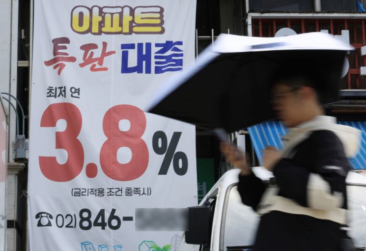 지난 15일 서울 시내 은행 앞 대출 홍보물을 지나는 시민. 연합뉴스