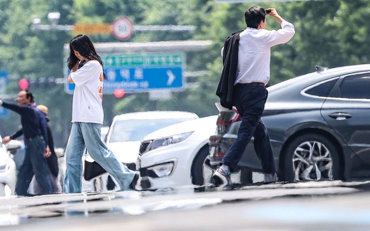 시민들이 지열로 인한 아지랑이가 피어오르는 도로를 건너고 있다. 연합뉴스