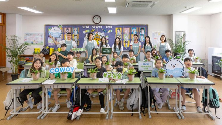 코웨이 임직원 봉사자들과 초등학생들이 청정학교 교실숲 제7호 조성 기념 단체 사진을 찍고 있다. 코웨이