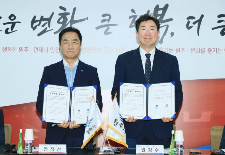 16일 원주시청에서 열린 자매결연 협약식에서 정장선 평택시장(왼쪽)과 원강수 원주시장이 협약서를 들어보이고 있다. 평택시 제공