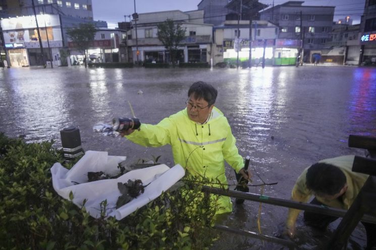 강기정 광주시장이 17일 오후 폭우로 침수된 북구 신안교 일대를 돌며 배수로를 막은 플라스틱, 비닐 등의 쓰레기를 직접 치우고 배수 상황을 점검하고 있다. 광주시 제공