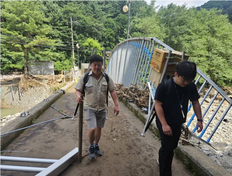 경기 가평군 연인산도립공원 직원들이 폭우로 고립된 주민들을 위해 지게에 생활필수품 등을 지고 나르고 있다. 경기도 제공