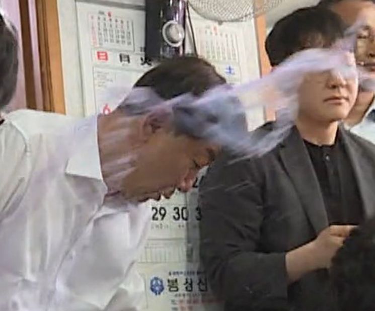 우범기 전주시장이 25일 오전 11시50분쯤 전북 완주군 봉동의 한 식당에서 전주시-완주군 통합 반대 군민으로부터 '물벼락'을 맞고 있다. 연합뉴스