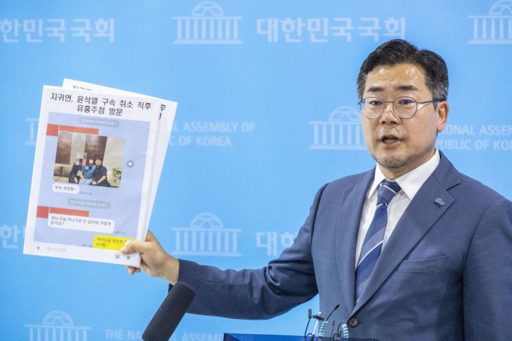 더불어민주당 당 대표 후보에 출마한 박찬대 의원이 27일 국회기자회견 뒤 가진 취재진과 인터뷰에서 제보로 입수한 지귀연 판사의 윤석열 전 대통령 구속 취소 직후 유흥주점 방문 관련 대화방 자료를 공개하고 있다. 연합뉴스