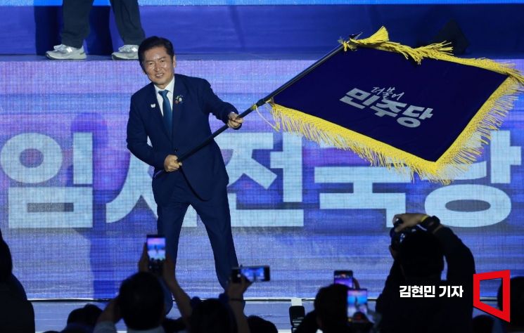 정청래 더불어민주당 신임 당대표가 2일 경기 고양시 킨텍스에서 열린 전국당원대회에서 김병기 당대표 직무대행 겸 원내대표로부터 받은 당기를 흔들고 있다. 2025.8.2 김현민 기자