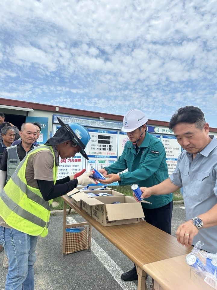 Jaehyuk Lee, president of Gyeongbuk Development Corporation (right), is handing out beverages to construction site workers laboring in the heat.