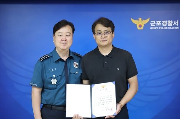 모텔 업주 A씨(오른쪽)가 보이스피싱 범죄 피해를 막은 공로를 인정받아 감사장을 수여받고 있다. 경기 군포경찰서