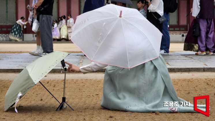비 내리는날, 경복궁을 찾은 한 외국인 관광객이 소중한 휴대폰이 젖을새라 셀카 한장을 찍기 위해서 휴대폰 위에 우산을 씌우는 모습이 정감 있다. 조용준 기자