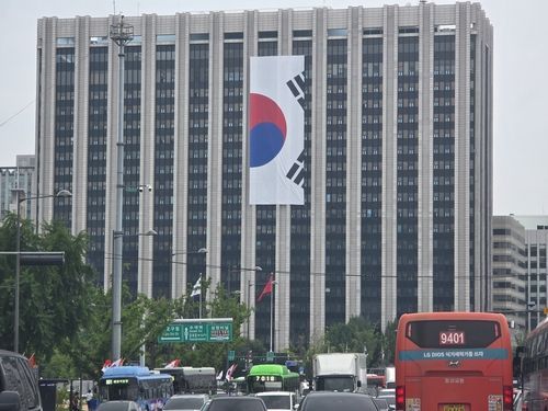 11일 정부서울청사 외벽 대형 태극기 게양 작업 중 조각난 태극기가 걸려 있는 모습. 연합뉴스