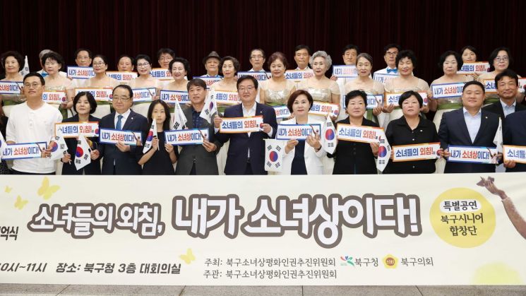 12일 광주 북구청에서 열린 ‘소녀들의 외침, 내가 소녀상이다!’ 기념 행사에서 참석자들이 손팻말과 태극기를 들고 일본군 위안부 피해자들의 명예 회복을 다짐하고 있다. 북구 제공